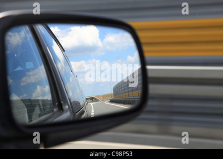 Riflettendo su strada nella veduta laterale specchio di una automobile Foto Stock