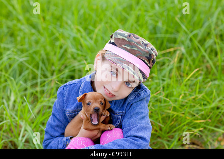 Bambina con cucciolo mascotte pinscher mini in outdoor erba verde Foto Stock