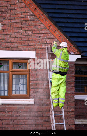 Uomini su scale  isolamento parete cavità alloggiamento tallone in polistirene, lavoratori in imbracature di sicurezza, installazione isolamento in schiuma a Southport, Regno Unito Foto Stock