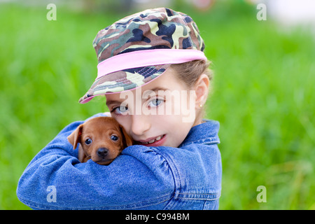 Bambina con cucciolo mascotte pinscher mini in outdoor erba verde Foto Stock