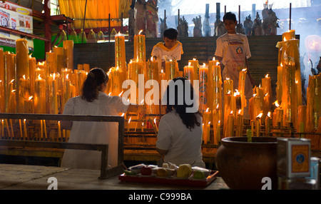 Gli operatori in bianco mantenere acceso candele durante il Festival vegetariano al San Jao Sien Khong santuario cinese a Bangkok. Foto Stock