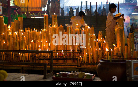 Gli operatori in bianco mantenere acceso candele durante il Festival vegetariano al San Jao Sien Khong santuario cinese a Bangkok. Foto Stock