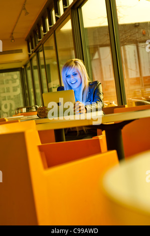 A sedici anni dai capelli biondi slim ragazza adolescente, utilizzando un Apple iPad, lettura e-mail Facebook ridere, REGNO UNITO Foto Stock