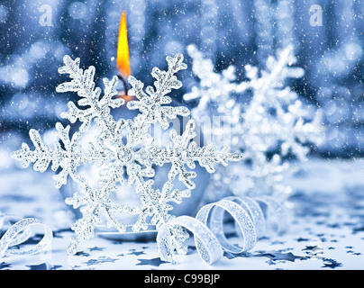 Bella decorazione di Natale, vacanze blu dello sfondo con la luce di una candela e il simbolo del fiocco di neve, vacanze invernali celebrazione, soft focus Foto Stock