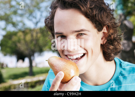 L'Italia, Toscana, Magliano, Close up del giovane uomo mangiare pera, sorridente, ritratto Foto Stock