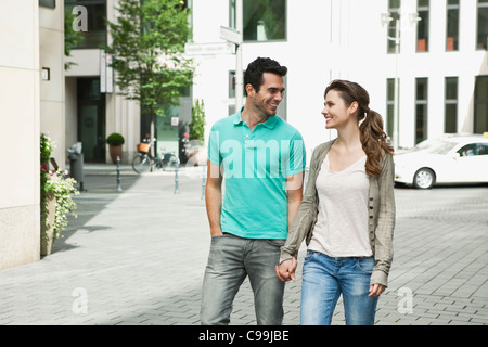 Germania, Berlino, giovane camminando mano nella mano attraverso una strada di città Foto Stock