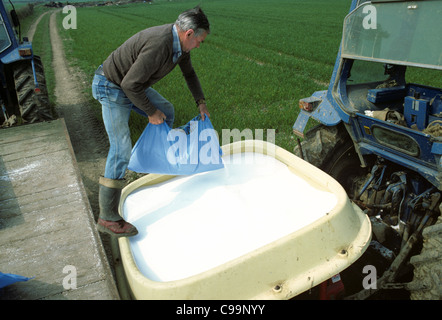 Agricoltore il riempimento di trattore montato tramoggia fertilizzante con fertilizzante di azoto (ICI Nitram) Foto Stock