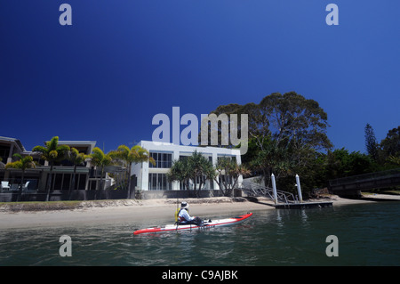 Kayaker passando per la sistemazione di case nel Canal Station Wagon presso Noosa Sunshine Coast, Queensland, Australia. No signor o PR Foto Stock