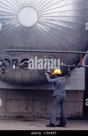 Lavoratore regola una valvola in corrispondenza di una raffineria di petrolio, Germania Foto Stock