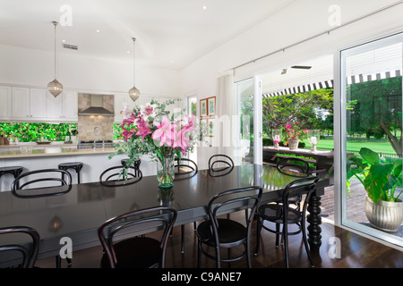 Elegante cucina a pianta aperta con elettrodomestici in acciaio inox e area da pranzo che si affaccia su una piscina e un campo da golf Foto Stock