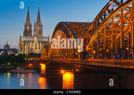 La cattedrale di Colonia e ponte di Hohenzollern dopo il tramonto Foto Stock