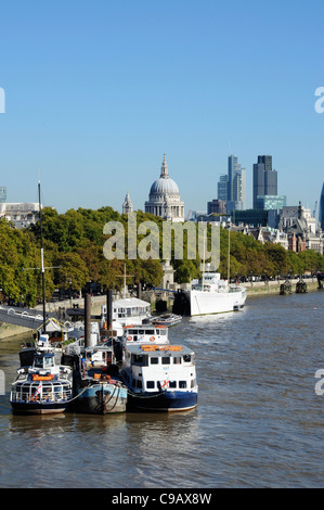 Barche ormeggiate lungo il fiume Tamigi con la cupola della cattedrale di St Paul e gli edifici della città dietro, London, England, Regno Unito Foto Stock