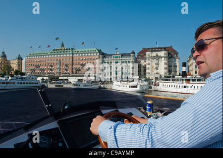 L'uomo la sterzatura di un motoscafo porto di Stoccolma, Svezia Foto Stock