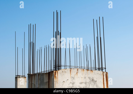 Vecchio acciaio di rinforzo sporgente dal calcestruzzo. Cielo blu sullo sfondo Foto Stock