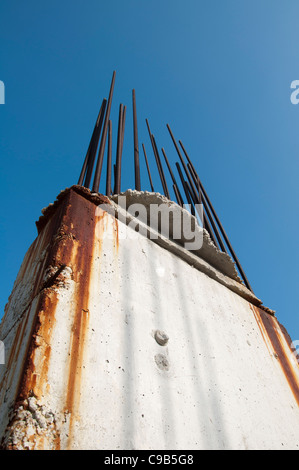 Vecchio acciaio di rinforzo sporgente dal calcestruzzo. Cielo blu sullo sfondo Foto Stock
