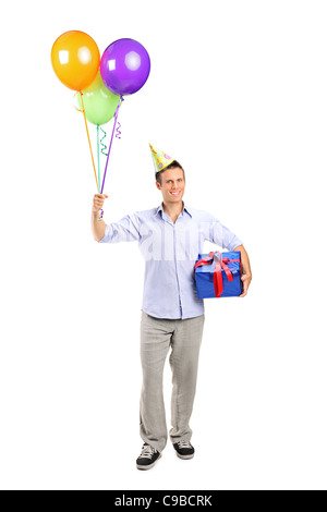 A piena lunghezza Ritratto di un sorridente giovane tenendo un presente e palloncini Foto Stock