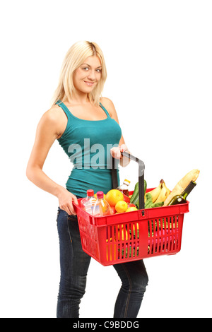 Una giovane donna tenendo un carrello pieno di negozi di generi alimentari Foto Stock