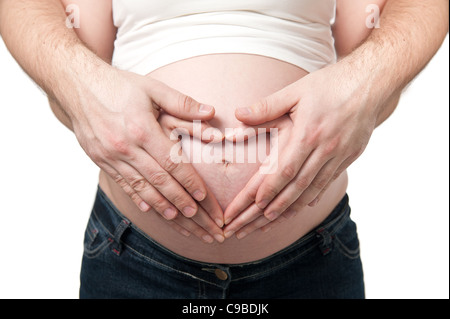 Le mani del giovane è realizzato nella forma di un cuore il ventre della donna incinta, isolato su sfondo bianco Foto Stock