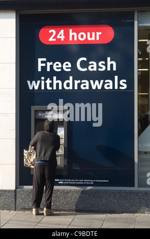 Donna al bancomat RBS attaccata alla Tesco Metro store, St Peter's Street, centro città, St Albans, England, Regno Unito Foto Stock