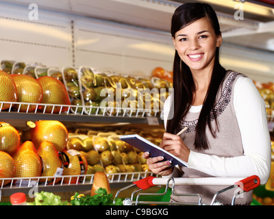 Immagine della bella donna che guarda la fotocamera mentre la scelta dei prodotti nel supermercato Foto Stock