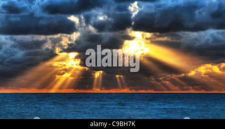 Tramonto spettacolare raggi attraverso un nuvoloso cielo scuro oltre oceano. Foto Stock