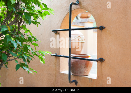 Angolo del giardino, parete arcuata foro con vuoto vaso di fiori da un albero verde Foto Stock