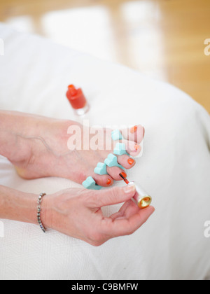 Senior donna pittura toenails, close up Foto Stock