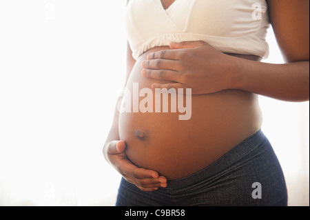 Vista ravvicinata della donna e delle sue mani cullano incinta dello stomaco, Johannesburg, provincia di Gauteng, Sud Africa Foto Stock