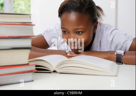 Femmina studente adolescente di lettura, con la pila di libri di fronte a lei, Cape Town, Provincia del Capo Occidentale, Sud Africa Foto Stock