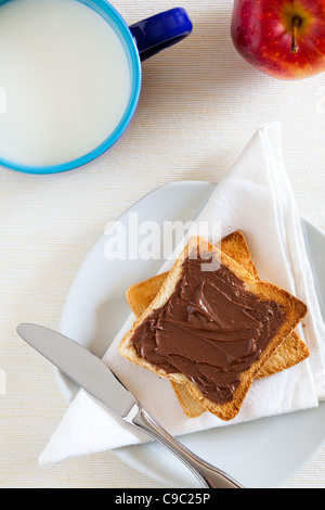 La prima colazione con cioccolato da spalmare sul pane tostato e latte Foto Stock