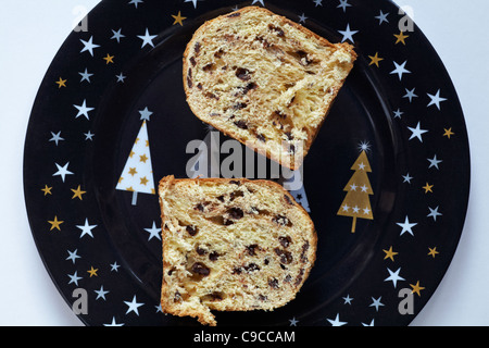 Gocce di cioccolato il panettone tagliato a metà e posto sul Natale decorativo piastra e impostare contro uno sfondo bianco Foto Stock