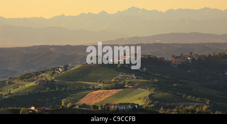 Vista panoramica sulle colline e villaggi contro le montagne al tramonto in Piemonte, Italia settentrionale. Foto Stock