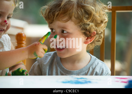 Bambina tergi della vernice sul suo fratello del volto Foto Stock