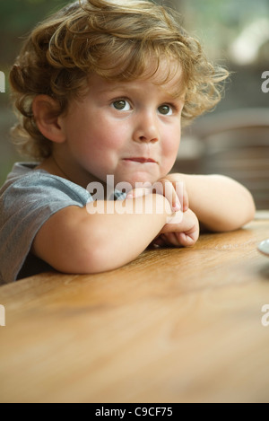 Little Boy mento di appoggio sui bracci, guardando lontano nel pensiero, ritratto Foto Stock