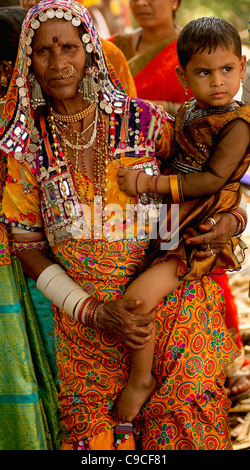 India, Karnataka, Lambani donna gitana tenendo il bambino. Tribal abitanti delle foreste, ora risolta in 30-home casali rurali. Foto Stock