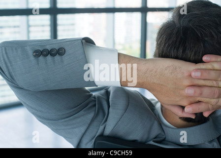 Imprenditore con le mani dietro la testa, vista posteriore Foto Stock