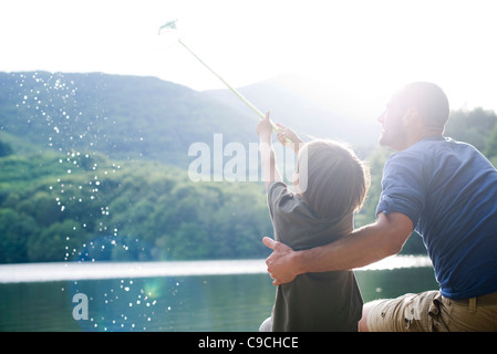 Padre e figlio la pesca, ragazzo pesce pescato in rete da pesca Foto Stock