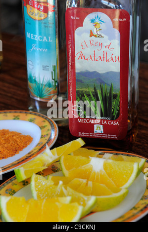 Messico, Oaxaca, bottiglie di Mezcal e piastra di fettine di arancia. Foto Stock