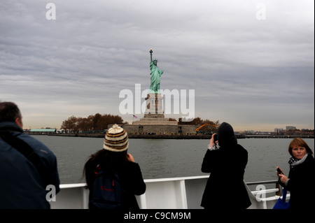 Turistica prendendo la fotografia della statua della libertà da un viaggio in barca Manhattan New York New York STATI UNITI D'AMERICA America Foto Stock