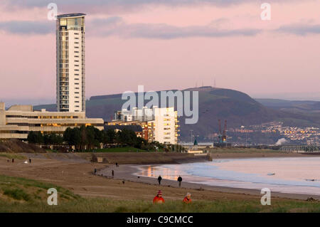 Walkers rendono la maggior parte della serata sole sulla Baia di Swansea in Galles del Sud su un nitido pomeriggio d'autunno. Foto Stock