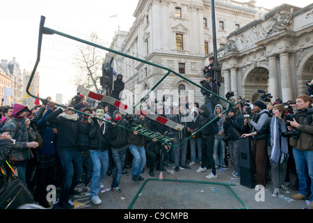 Manifestanti mascherati gettando una barriera alla polizia su Whitehall, giorno X manifestazione studentesca, 24 novembre 2010, Londra, Inghilterra Foto Stock