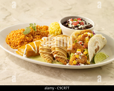 Un gambero taco, due empanadas e un tamale coperti in salsa servita con lo spagnolo di riso e fagioli neri Foto Stock