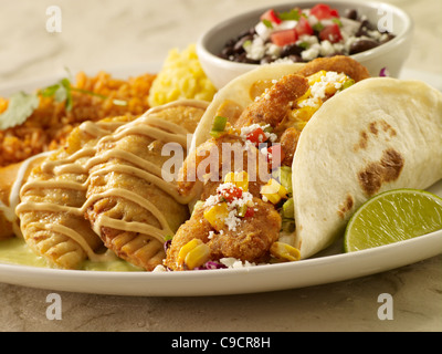 Un gambero taco, due empanadas e un tamale coperti in salsa servita con fagioli neri e riso spagnolo Foto Stock