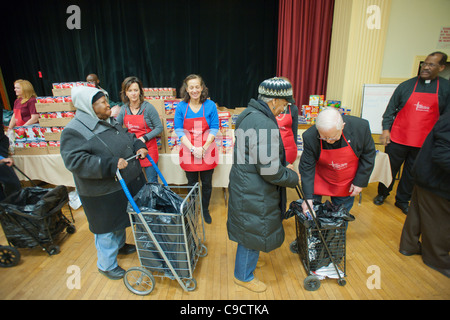 Volontari distribuiscono i tacchini, imbottitura e tutti gli altri "fixin's" per una cena di ringraziamento per i più bisognosi Foto Stock