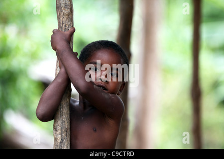 Un giovane malgascio ragazzo nero azienda ad un palo di legno in Ankify, Madagascar settentrionale, Africa Foto Stock