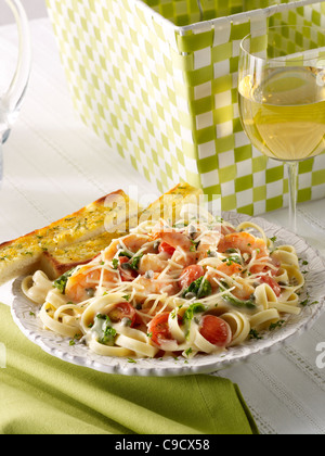 Gamberetti pasta con verdura conditi con formaggio Parmigiano servito con pane all'aglio e un bicchiere di vino bianco Foto Stock