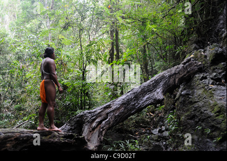 L'uomo indigeno di Embera meditava da solo nella giungla mentre si trovava su un tronco di alberi caduto nella comunità indigena di Embera nella foresta pluviale di Panama. Foto Stock