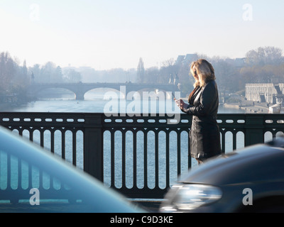 L'Italia, Piemonte, Torino, Donna attraversando a piedi il ponte di inviare un messaggio di testo Foto Stock