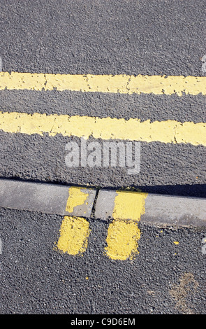 Doppio giallo di parcheggio e di carico delle linee di restrizione dipinta su una strada e il cordolo. Foto Stock