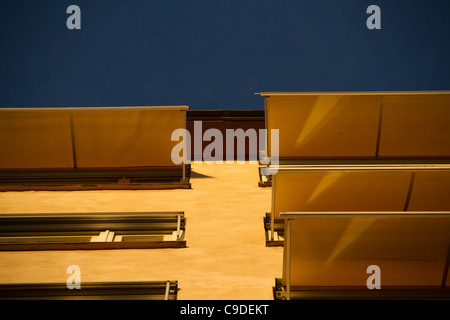 Bassa foto angolata di edificio giallo con persiane di ombra al tramonto contro il cielo blu Foto Stock